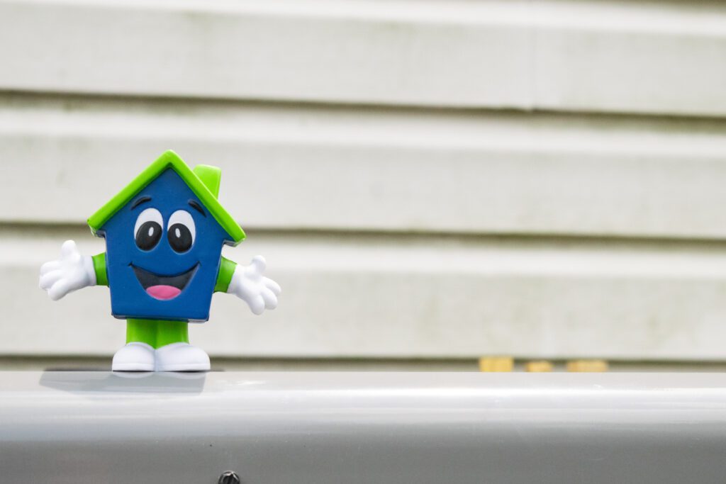 Happy House mascot toy in front of home