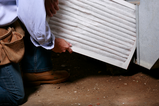 An HVAC technician changing a furnace's air filter in an Erlanger, KY, home.