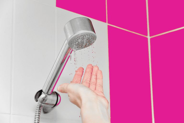 Homeowner holding hand under showerhead as it leaks due to low water pressure