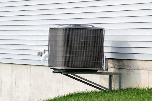 An AC unit on a raised platform outside of a house.