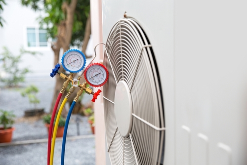 Close-up of HVAC installation with pressure gauges connected to an air conditioning unit.